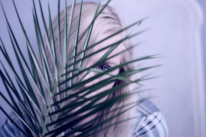 Passive girl hiding behind fern